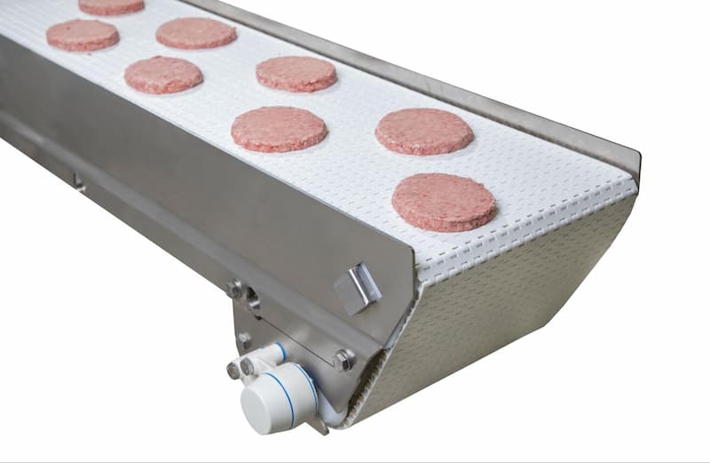 A Dorner AquaPruf conveyor belt transports hamburger patties.
