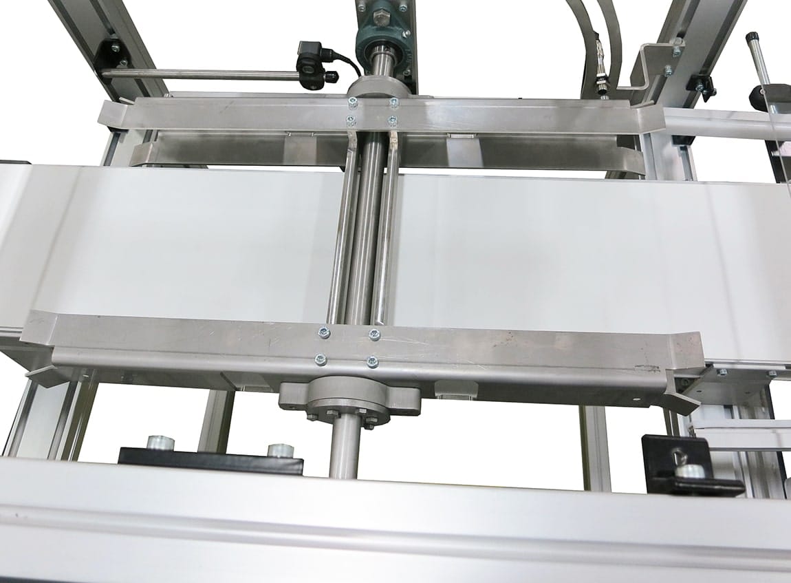 A conveyor with an obstruction at the center of the belt to flip products during processing.